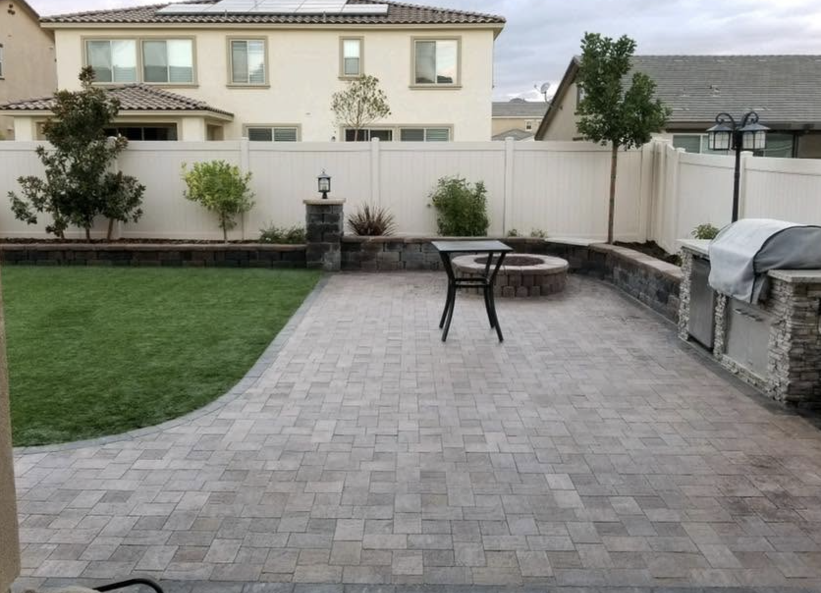 Finished backyard with a paver patio, fire pit, seat wall, BBQ island and fresh turf