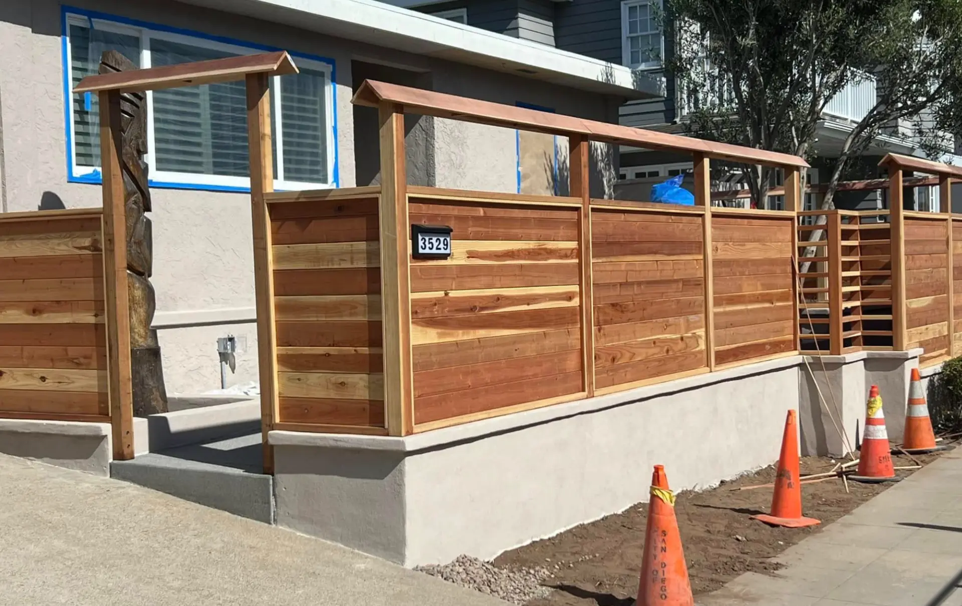 New horizontal wood fence with a stained finish on a front yard stucco wall