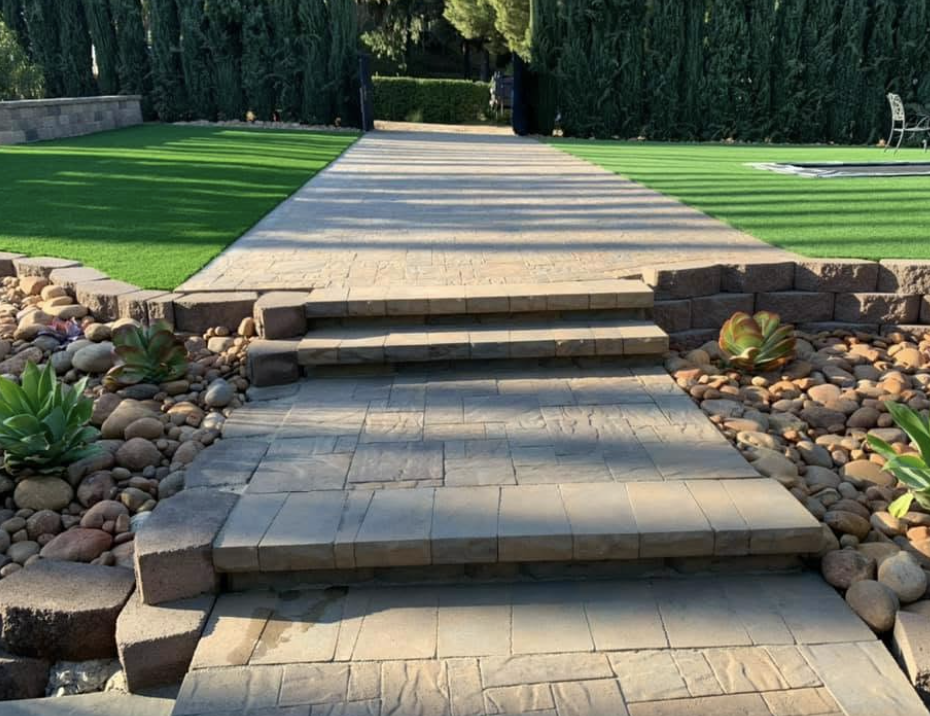 Long paver walkway with block steps between two strips of artificial turf