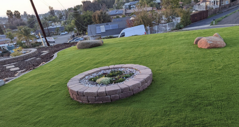 Fresh artificial turf on a slope with a stone-edged planter