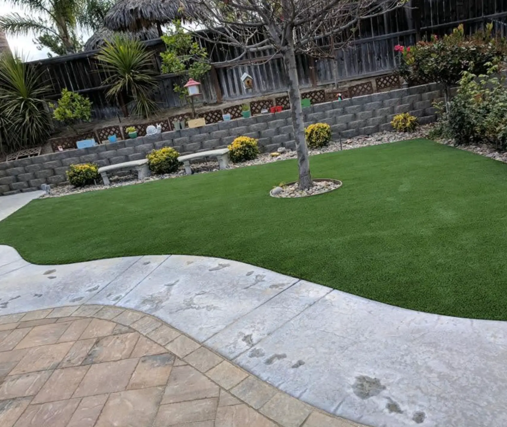 Finished artificial turf lawn with terraced block retaining walls and a paver walkway