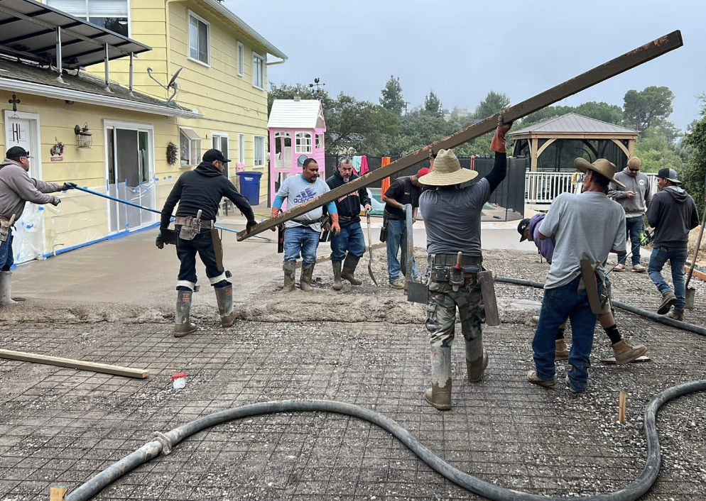 Crew pouring and leveling a concrete patio slab over rebar